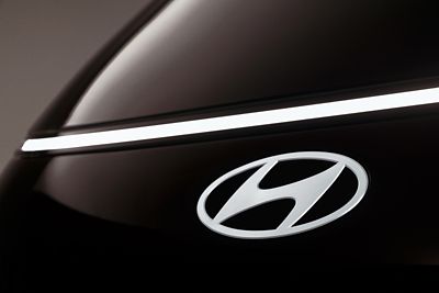 Close up view of the front Hyundai emblem of the STARIA Electric.