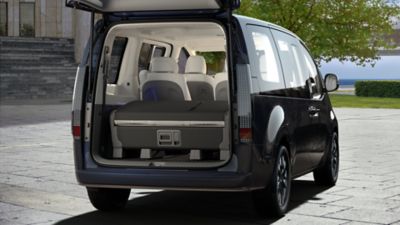 A man walking away from the smart power tailgate of the Hyundai STARIA Hybrid multi-purpose vehicle.