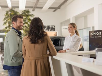 Muž a žena stojící na recepci u autorizovaného prodejce značky Hyundai.