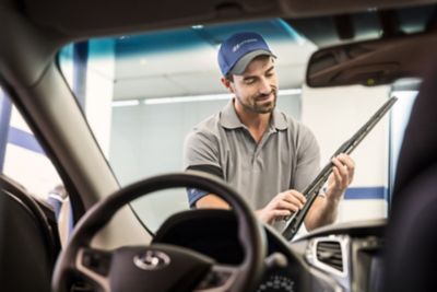 En mekaniker skifter vindusviskerer på en Hyundai. Foto.
