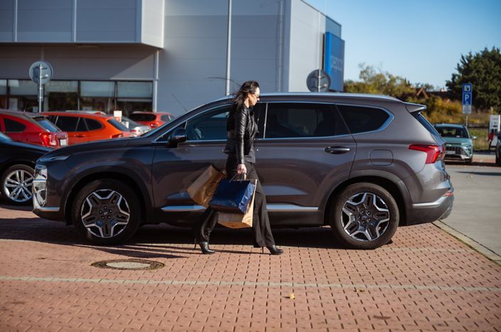 Šedý Hyundai SANTA FE Hybrid zaparkovaný na ceste pod stromami s jesenne sfarbeným lístím