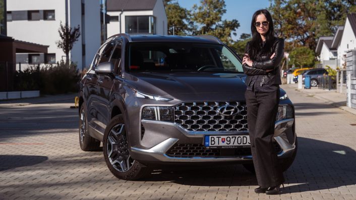 žena stojaca pred svojim šedým Santa Fe Hybrid na lici
