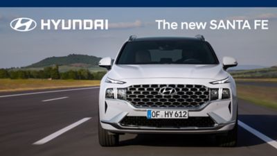 Nové 7místné SUV Hyundai Santa Fe Hybrid v bílé barvě jedoucí po dálnici.