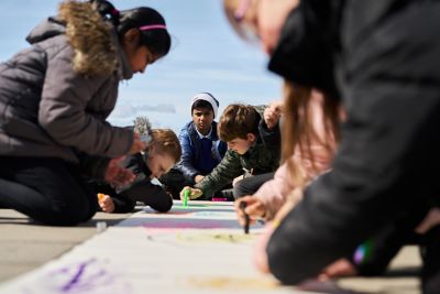 Schoolkids colouring in a large banner.