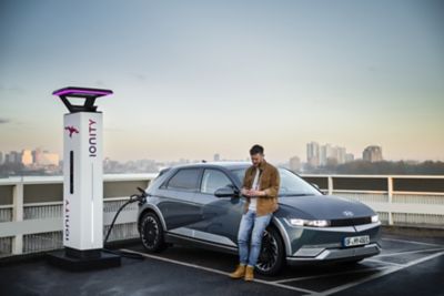 Ein Mann vor einem Hyundai IONIQ 5, der auf einem Parkdeck an einer IONITY-Ladesäule lädt.