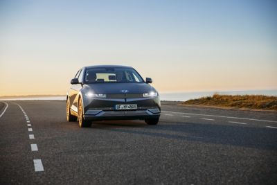 Ein IONIQ 5 bei Abenddämmerung auf einer Küstenstraße.