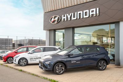 Hyundai Baion blu scuro e Hyundai 120 Hybrid bianca viste da davanti di tre quarti davanti alla vetrina dello showroom