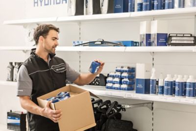 Ein Hyundai Service-Mitarbeiter räumt Hyundai Originalteile und Pflegemittel in ein Regal.