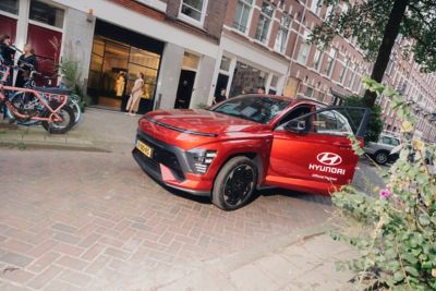 Twee modellen, een vrouw en een man, lopend op een catwalk met zittend publiek ernaast.