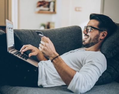 Man op de bank met laptop op schoot