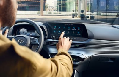 Bärtiger Mann am Steuer eines Hyundai wählt eine Fahrzeug-App über den Touchscreen-Bildschirm. 