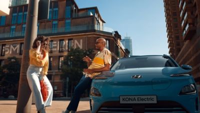 The Hyundai Kona Electric from the front in Dive in Jeju, with two people chatting.