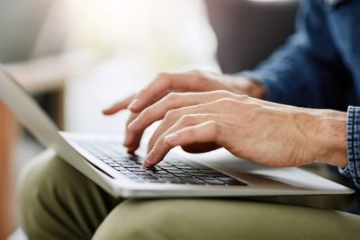 Mężczyzna piszący na klawiaturze laptopa