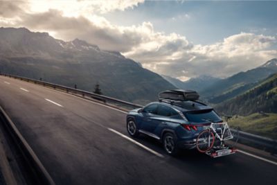 Hyundai with roof rack and bike rack drives in the mountains.