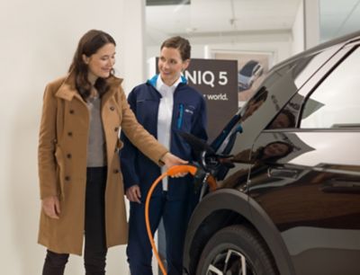 Verkoopster laat de klant zien hoe zij de auto moet opladen.
