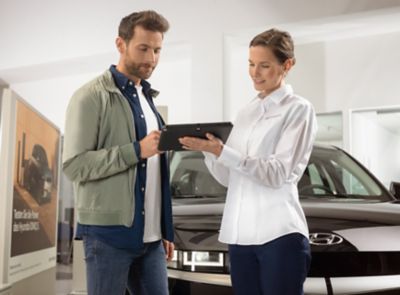 Ein Hyundai-Mitarbeiter steht vor einem Hyundai Elektroauto.