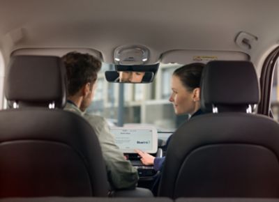 Hyundai employee sits with customer in car and explains media system.