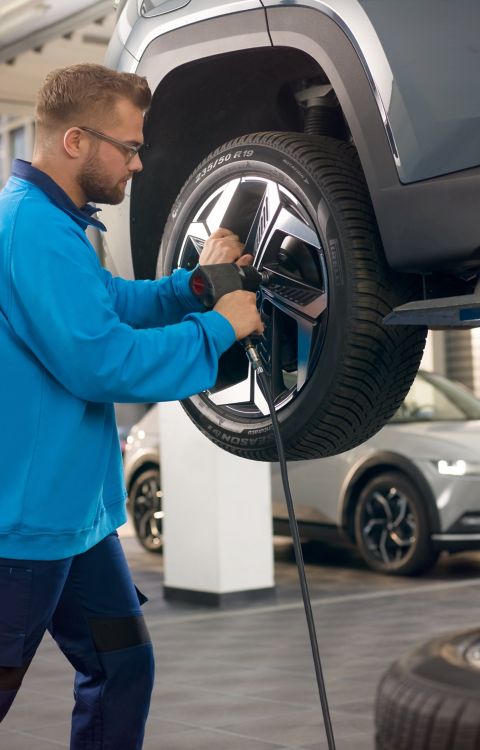 Trabajador taller realizando mantenimiento en ruedas.