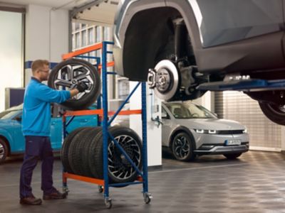 A Hyundai mechanic doing a wheel change in a Hyundai dealership garage.