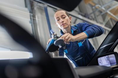 Kvinnlig biltekniker som arbetar med service på Hyundai-verkstad.