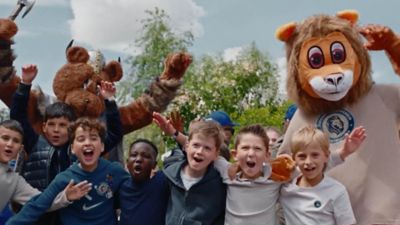 ein Gruppenfoto von Kindern, hinter denen zwei als Löwen verkleidete Männer stehen