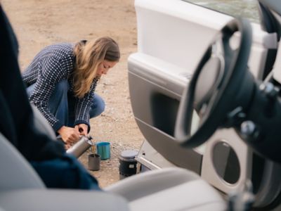 En kvinna häller upp en kopp kaffe utanför en Hyundai.