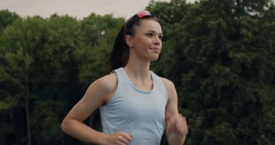 bezkyna v modrom tielku beziaca a sumevom ma na hlave bezecke okuliare