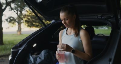 bezkyna sediaca v otvorenom batozinovom priestore siveho IONIQ 5. V ruke drzi flasu s napojom