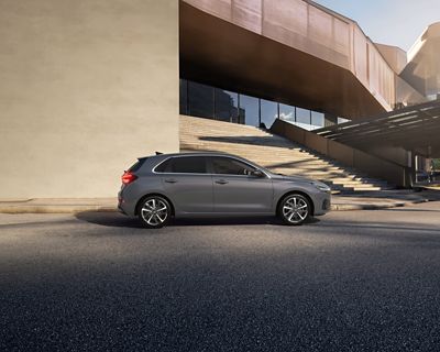 	 Vue latérale de Nouvelle Hyundai i30 en gris, garée devant un grand escalier extérieur.