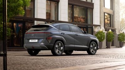 A grey Hyundai KONA rear view, in front of a building.