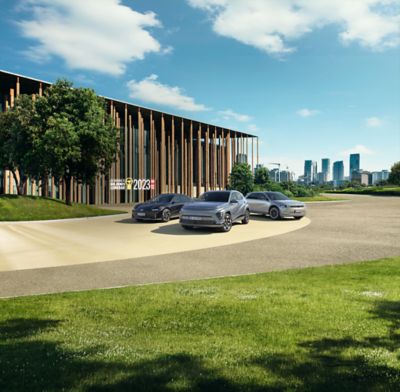 Die Hyundai Modelle IONIQ 5, IONIQ 6 und KONA Elektro vor einem holzverkleideten, modernen Gebäude am Stadtrand.