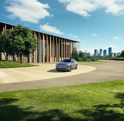 Der Hyundai KONA Elektro vor einem holzverkleideten, modernen Gebäude am Stadtrand.