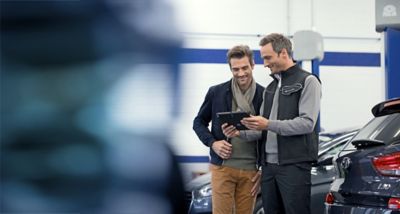 Ein Mann und ein Hyundai Service Mitarbeiter schauen auf einen Tablet-Computer.