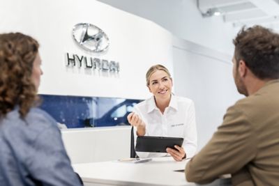 Hyundai fleet speaking to customer with tablet in hand.