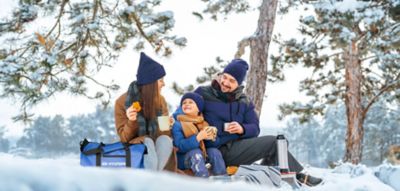 Familie in de sneeuw met Hyundai sporttas en warme chocolademelk