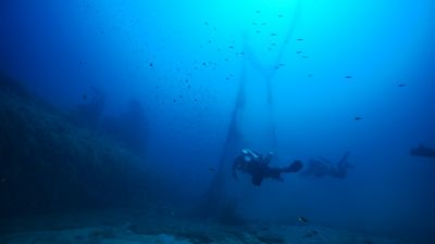 Two divers from Ghost Divers recovering marine debris underwater.