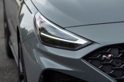 Young man leaning against the hood of his Hyundai i30 Fastback N