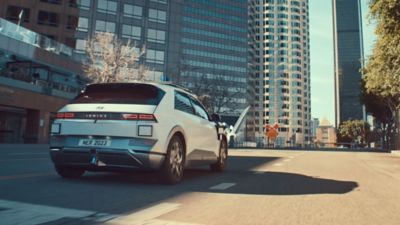 Plně elektrické robotaxi Hyundai IONIQ 5 při jízdě městskou ulicí zezadu.