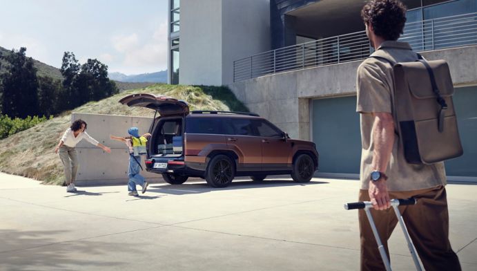 Matka s dietatom pri nakladani batoziny do zadneho kufra SANTA FE, otec kracajuci s kufrom smerom k nim