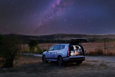 IONIQ 9 s otevřenými zadními dveřmi uprostřed noční přírody.