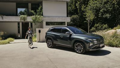 Hyundai TUCSON Plug-in Hybrid zaparkowany przed nowoczesnym domem.