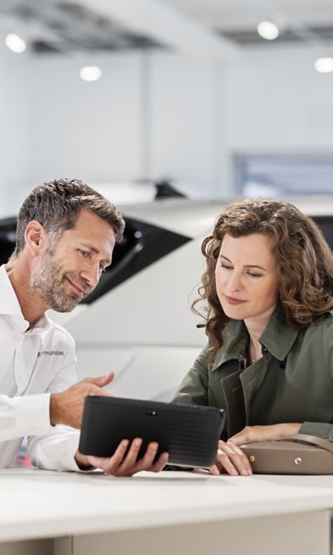 Vendedor usando una tablet con una cliente.