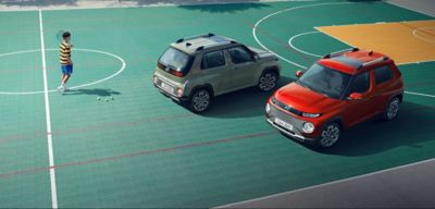Groene en rode Zuid-Koreaanse Hyundai Casper op een sportveld.