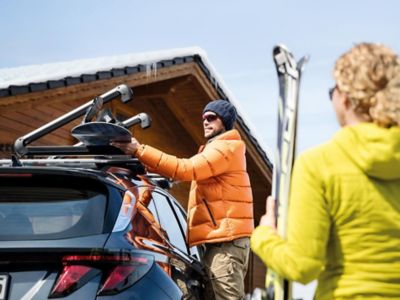 Man lyfter av skidutrustning från taklasthållare på Hyundai TUCSON.