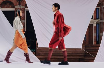Twee modellen, een vrouw en een man, in kleding van modemerk MARTAN lopend op een catwalk.
