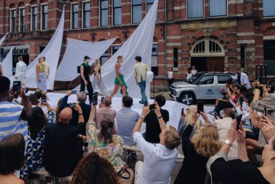 Diverse modellen, vrouwen en mannen, in kleding van modemerk MARTAN lopend op een catwalk.