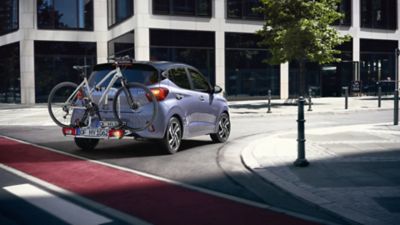 La Hyundai i10 roulant en ville avec un porte-vélos à l’arrière.