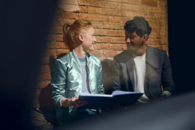 A man and a woman looking at each other in front of a brick wall