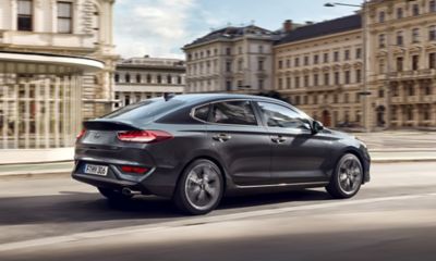 Der neue Hyundai i30 Fastback auf der Fahrt in einer städtischen Umgebung.