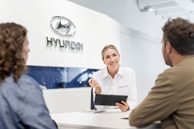 Mano di uomo che pulisce uno stemma Hyundai sulla griglia frontale di un'auto